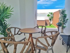 A patio area with wicker furniture, a round table, and potted plants. - Luxe Condo with/Rooftop @ Star (Bavaro)