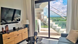 Ein modernes Wohnzimmer mit Fernseher, Holzschrank, schwarzem Couchtisch und Sofa.