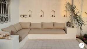 A beige sofa with cushions, a small table with a decorative item, and a potted plant.