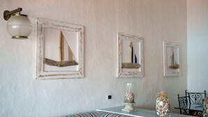 Een kamer met een wandlamp, drie ingelijste kunstwerken en een tafel met decoratieve objecten.