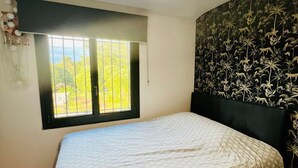 A bedroom with a bed, a window, and a wall with a floral pattern. - House in the heart of Provence (Flayosc)