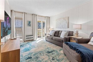 A modern living room with a sofa, a coffee table, and a TV. - Ocean View Shore Drive Bliss- Pool- Grills- Slps 6 (Myrtle Beach)
