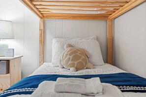 A bedroom with a wooden headboard, a white bedspread, a blue blanket, and a turtle-shaped pillow. - Ocean View Shore Drive Bliss- Pool- Grills- Slps 6 (Myrtle Beach)