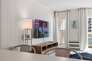 Une chambre d  ’hôtel équipée d’un téléviseur à écran plat fixé au mur, d’une table de chevet, d’une lampe, d’une fenêtre avec des rideaux et offrant une vue sur l’extérieur.