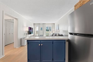 A modern kitchen with a built-in island, stainless steel appliances, and a view to the outside. - Ocean View Shore Drive Bliss- Pool- Grills- Slps 6 (Myrtle Beach)