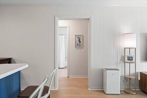 Une cuisine moderne avec un plan de travail blanc, une chaise en bois et un réfrigérateur blanc.