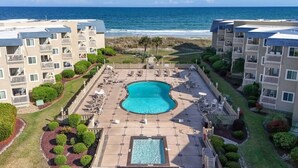 A resort with a central pool, multiple balconies, and a view of the ocean.