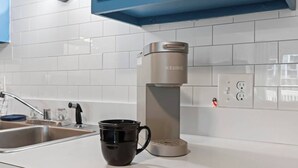 A modern kitchen with a coffee maker, a sink, and a countertop.