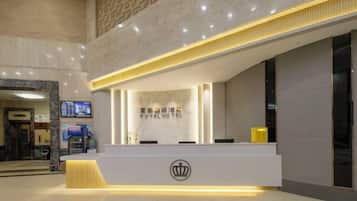 Zona de recepción de un hotel con diseño moderno, mostrador de recepción y pantalla digital.