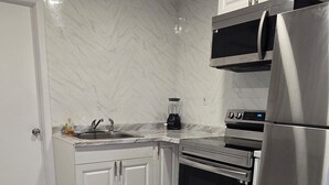 A modern kitchen with white cabinets, a stainless steel refrigerator, a microwave, and an oven. - Charming studio with AC and WiFi in brilliant Tampa (Tampa)