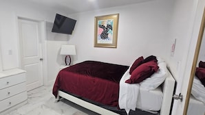 A bedroom with a bed, a dresser, a TV, and a framed picture on the wall. - Charming studio with AC and WiFi in brilliant Tampa (Tampa)