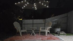 An outdoor patio with two chairs and a table under a string-lit umbrella. - Charming studio with AC and WiFi in brilliant Tampa (Tampa)