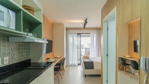 A modern kitchen with a microwave, a dining area with a table and chairs, and a bedroom with a bed and a window. - Cozy Near Allianz Parque Sp-p1609a (São Paulo)