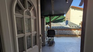 A view through a door into a covered outdoor area with a barbecue grill and a covered table. - Apartamento a 5 minutos de Luxemburgo fully equipped kitchen, lovely terrace (Audun-le-Tiche)