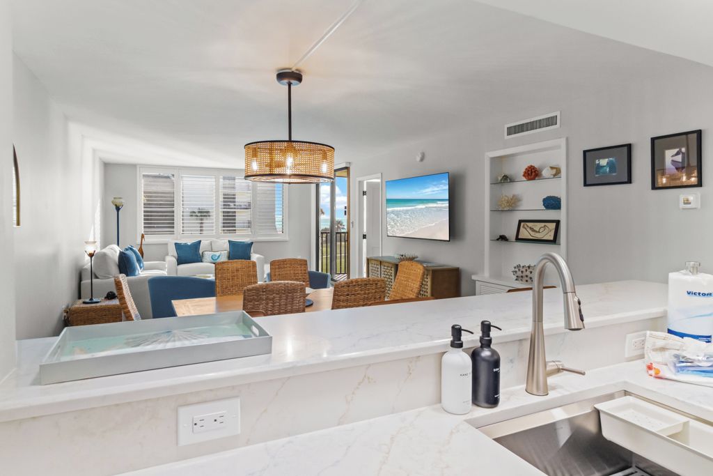 A modern kitchen with a marble countertop, a built-in sink, and a hanging light fixture.