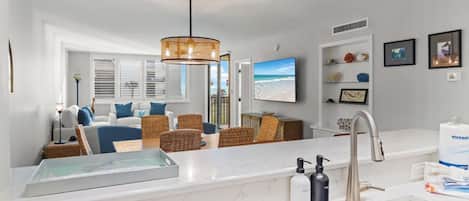 A modern kitchen with a marble countertop, a built-in sink, and a hanging light fixture.
