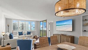 Un salon moderne doté d’une grande fenêtre, d’une table à manger et d’une décoration murale sur le thème de la plage.