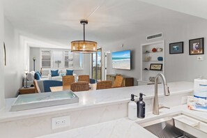 Une cuisine moderne dotée d’un plan de travail en marbre, d’un évier encastré et d’un luminaire suspendu.