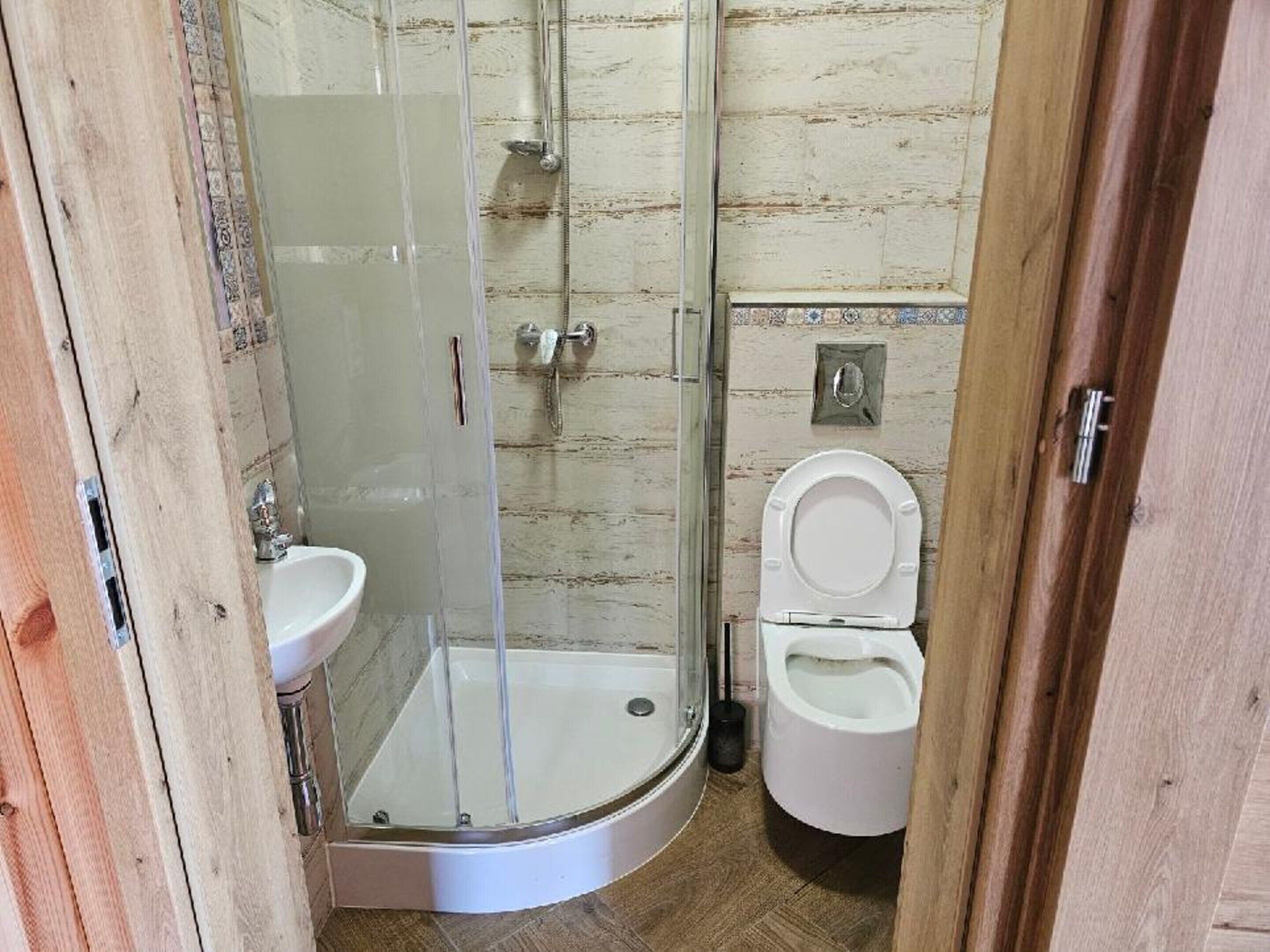 Un baño con ducha de vidrio, lavamanos y retrete.