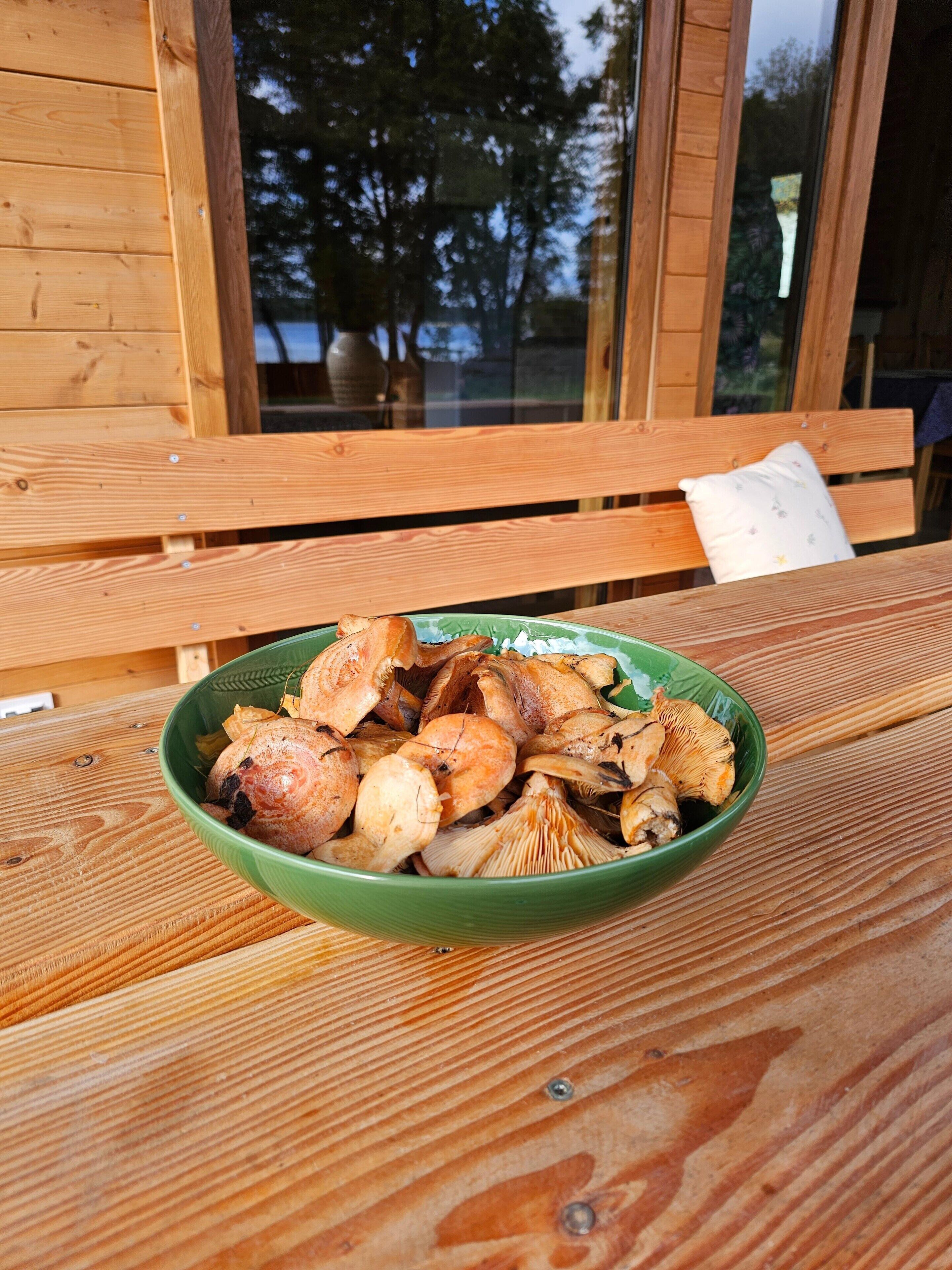A wooden table with a bowl of mushrooms.