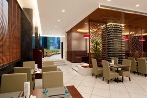 A modern hotel lobby with a seating area, a staircase, and a decorative wall with a wine rack.