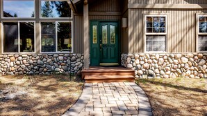 A house with a green door, stone walls, and a brick pathway leading to the entrance. - OREG36-Family and Dog Friendly Retreat w. AC (Sunriver)