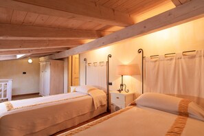Ein Zimmer mit zwei Betten, Holzbalken an der Decke, einem Nachttisch mit Lampe und einem Kleiderschrank.