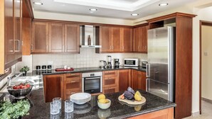 A modern kitchen with wooden cabinets, stainless steel appliances, and a granite countertop. - Villa Prengos 6 (Neo Chorio)