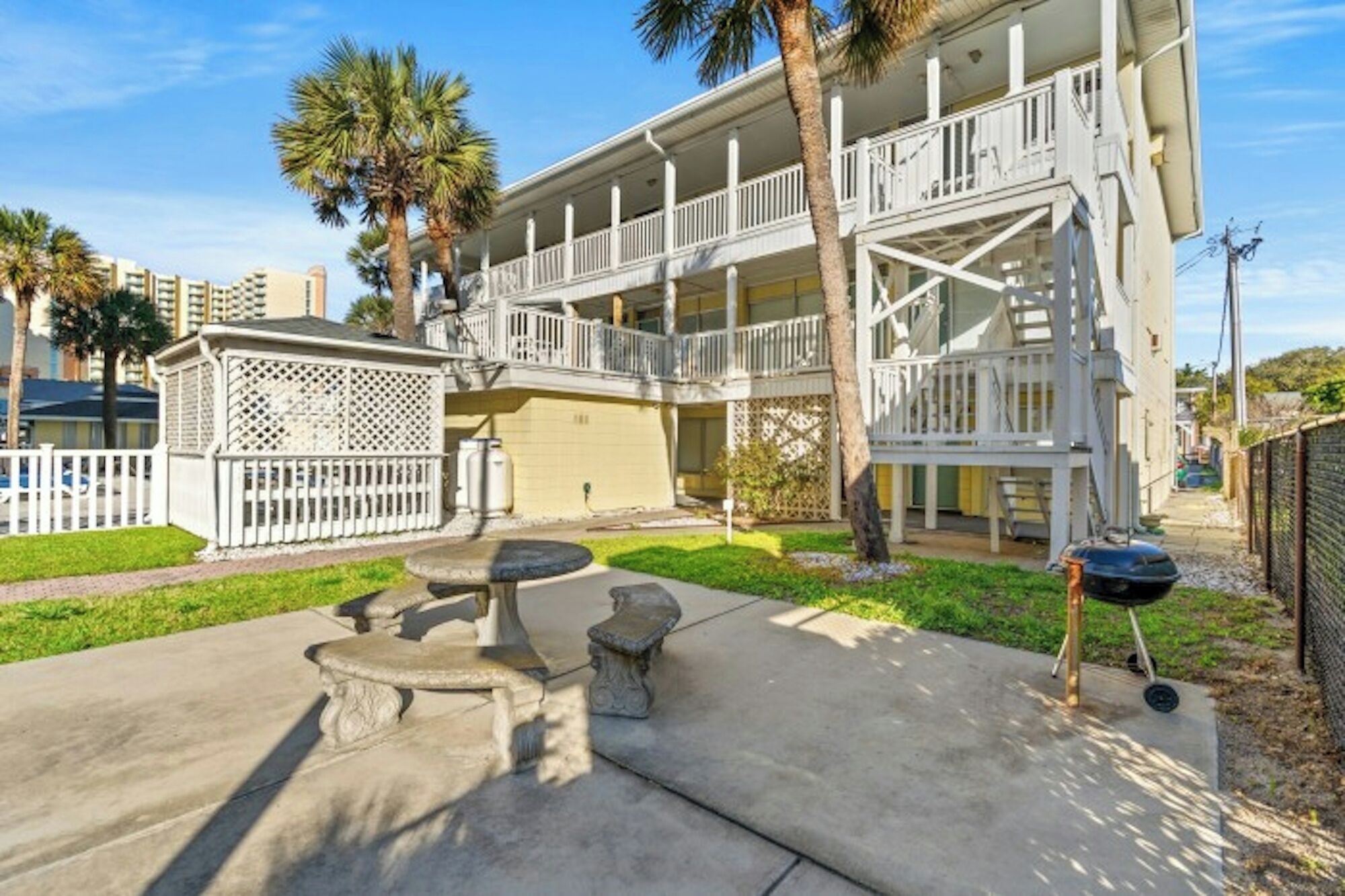 A two-story building with a balcony, a covered outdoor seating area, and a small garden.