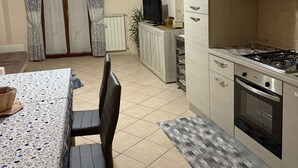 Una cocina moderna con estufa a gas, horno y alacenas. Hay un comedor con mesa y sillas.