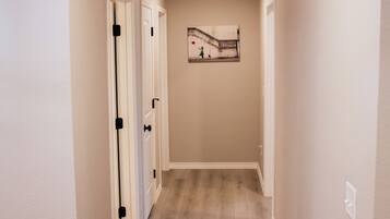 A hallway with wooden flooring, white walls, and a ceiling light.
