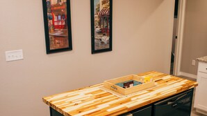 A kitchen with a wooden countertop, black cabinets, and two framed pictures on the wall.