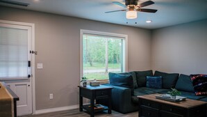 A living room with a dark green sofa, a wooden coffee table, and a small side table.