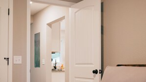 A bedroom with a bed, a door leading to a bathroom, and a mirror on the wall.