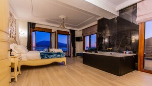Habitación de hotel con cama, zona de estar con vistas, espejo grande y baño con lavabo y espejo.