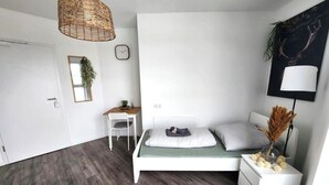 Een slaapkamer met een bed, nachtkastje, lamp en hanglamp.