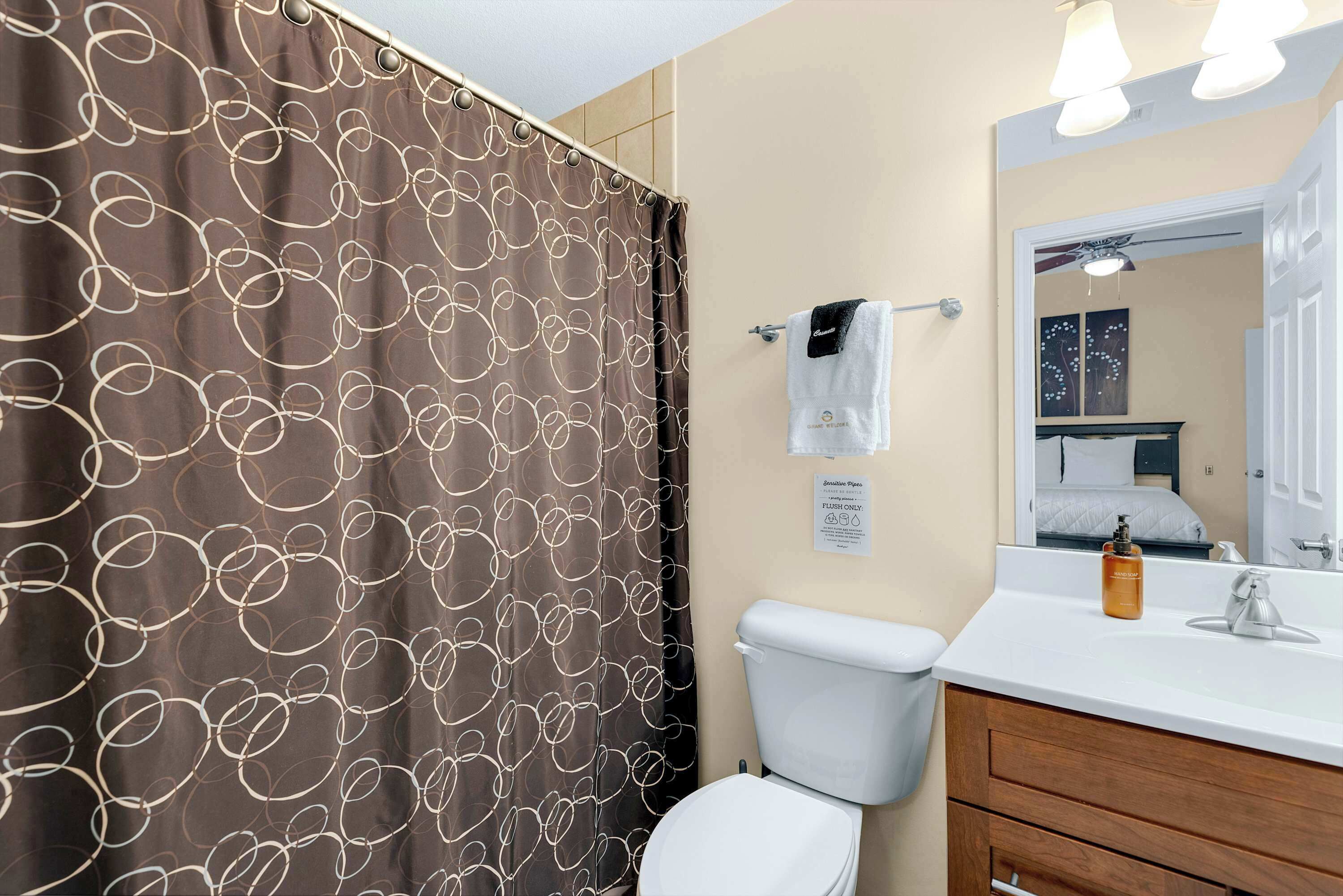 A bathroom with a toilet, a sink, a mirror, and a shower curtain with a circular pattern.