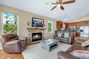 Una sala de estar moderna con chimenea, sofás de cuero, una mesa de centro y una cocina con electrodomésticos de acero inoxidable.