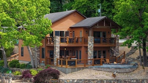A multi-story lodge with a stone facade, multiple balconies, and outdoor seating areas. - Trails End Hideaway Waterfront (Sunrise Beach)