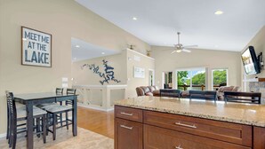 A spacious kitchen with a large island, wooden cabinets, and a dining area with chairs. - Trails End Hideaway Waterfront (Sunrise Beach)