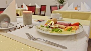 Een eettafel met een bord eten, een kaars en een vork.