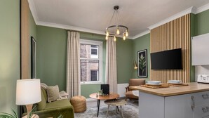 A modern living room with a sofa, a small round table, and a TV. - Ochill View Apartment by Stirling Train Station (Stirling)