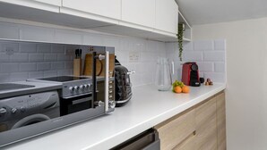 A modern kitchen with a built-in washer-dryer, a toaster, and a coffee maker on the counter. - Central Cathedral Apartment (Dunblane)