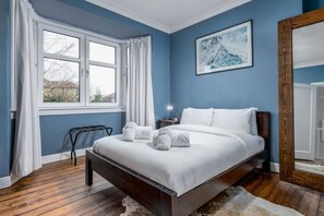 A bedroom with a bed, a nightstand, a lamp, and a window with curtains.