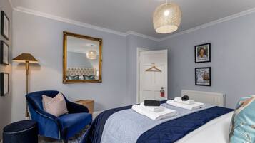 Une chambre à coucher comprenant un lit, une chaise, un miroir, un luminaire suspendu et des tableaux encadrés accrochés au mur.