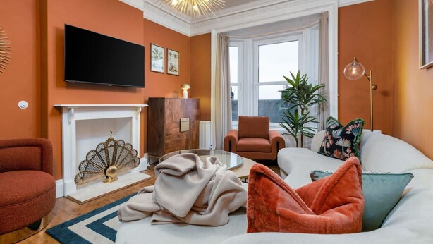 Una sala de estar con chimenea, televisor y un ventanal grande.