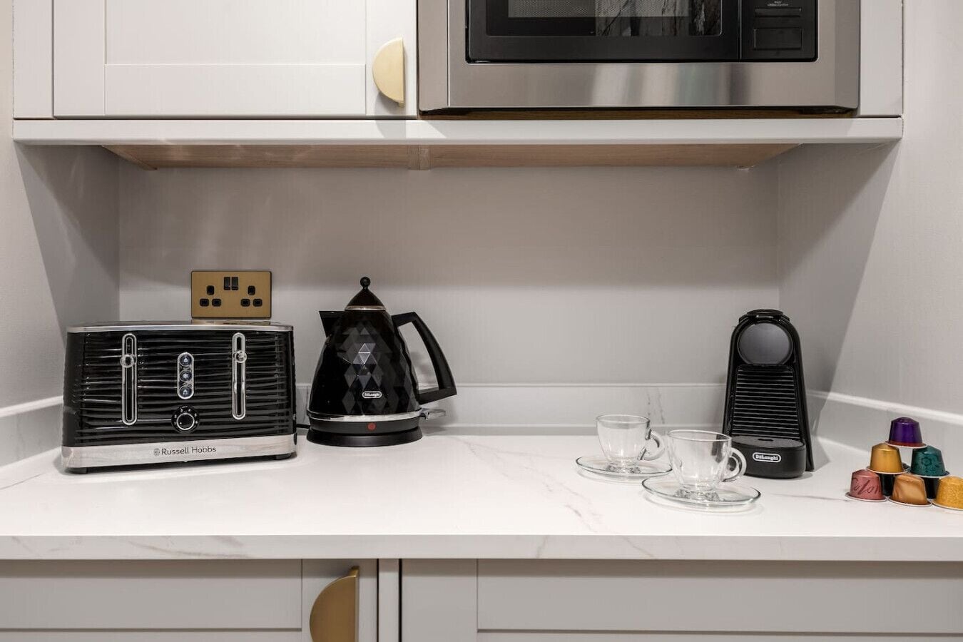 A kitchen with a vintage radio, a coffee maker, and a microwave on the countertop.