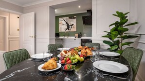 A dining area with a marble table set for a meal, surrounded by green upholstered chairs. - Emerald Suite, The Stirling Residence (Stirling)