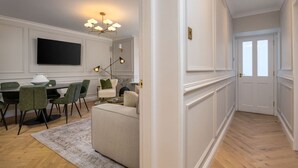 A modern living room with a dining area, a flat-screen TV, and a chandelier. - Emerald Suite, The Stirling Residence (Stirling)