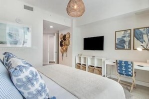 Un dormitorio moderno con cama, escritorio y televisor.